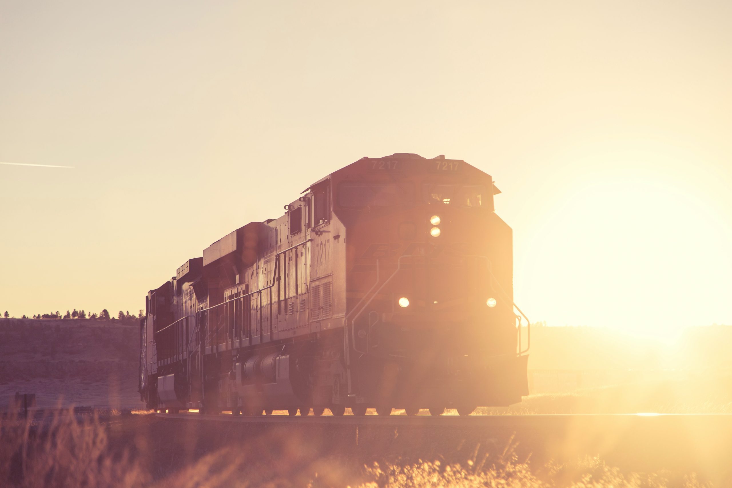 A rail train travelling past a sunset.